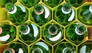 A collection of green glass bottles vertically arranged in a yellow container.